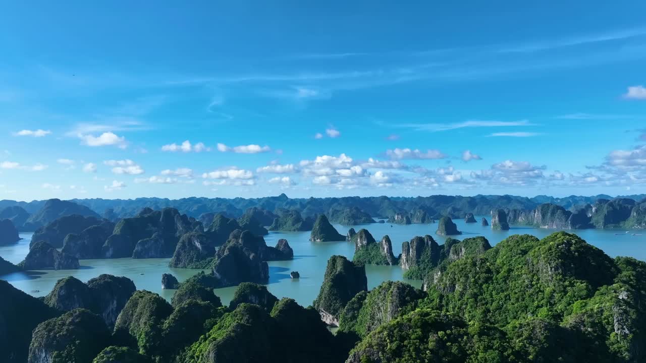 Cinematic drone capture of towering green karsts scattered across Halong Bay’s calm, jade waters, creating a stunning panorama that blends serenity, adventure, and the timeless beauty.