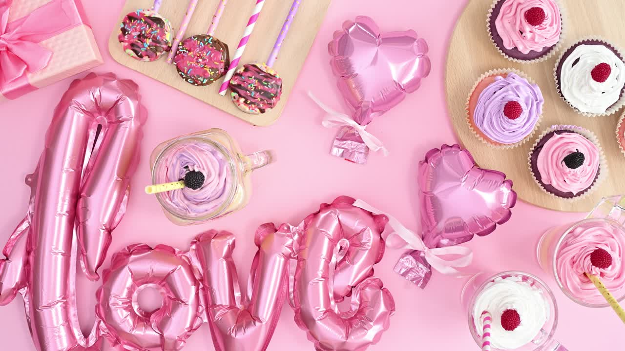 decoración del día de san valentín en la mesa con globos y dulces en color rosa pastel. detenga el movimiento