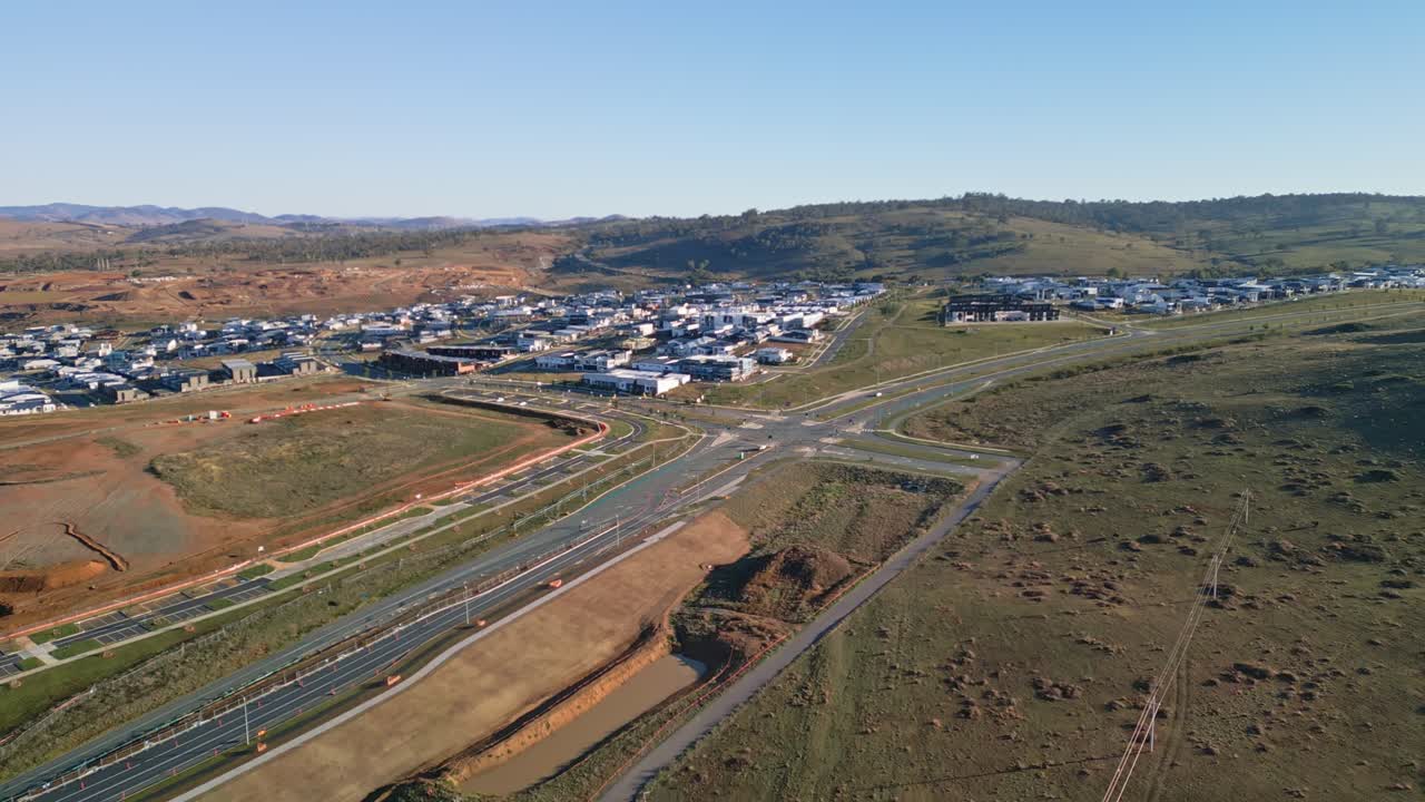 An aerial shot capturing a paddock adjacent to a cluster of newly constructed houses in Canberra, highlighting the city’s suburban expansion.