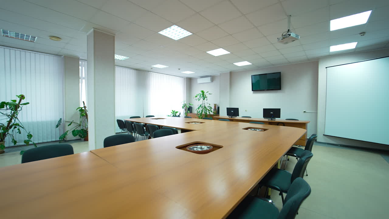 Conference hall in modern medical centre. Big light meeting room with long table and screen on the wall.