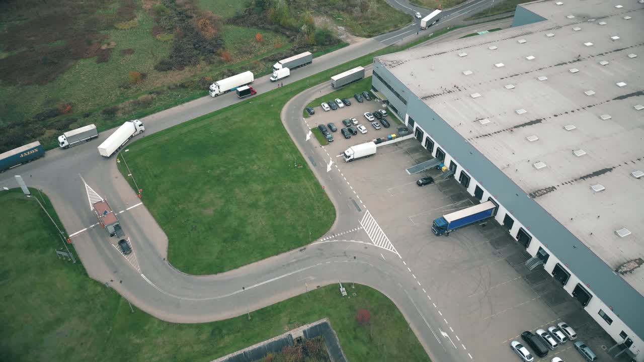 Buildings of logistics center, warehouses near the highway, view from height, a large number of trucks in the parking lot near warehouse