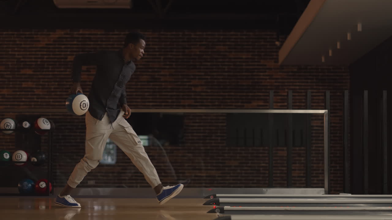 One black African-American man throws a bowling ball and knocks out a clash dancing jumping and singing rejoicing in victory