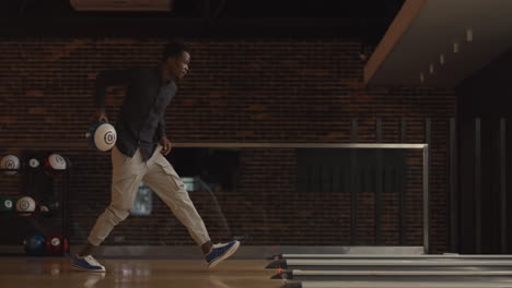 one black african-american man throws a bowling ball and knocks out a clash dancing jumping and singing rejoicing in victory