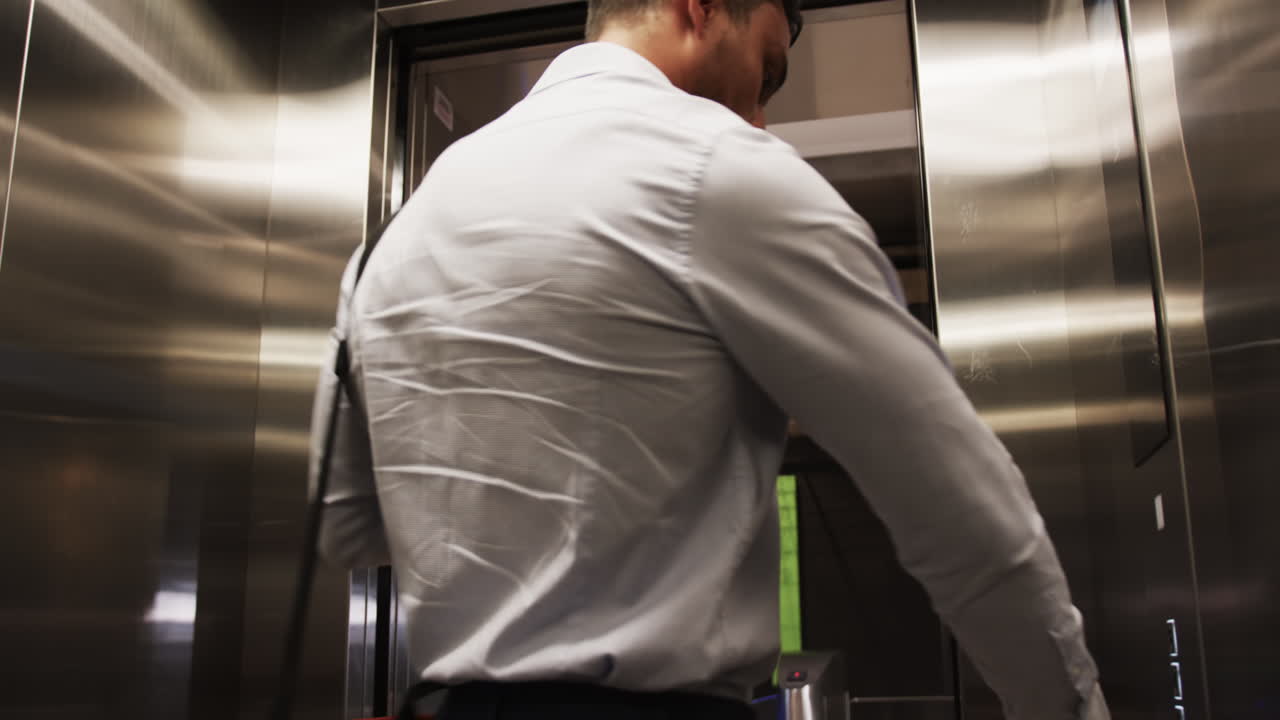 Entering office building, man in business attire waiting for elevator doors to open