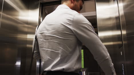 entering office building, man in business attire waiting for elevator doors to open