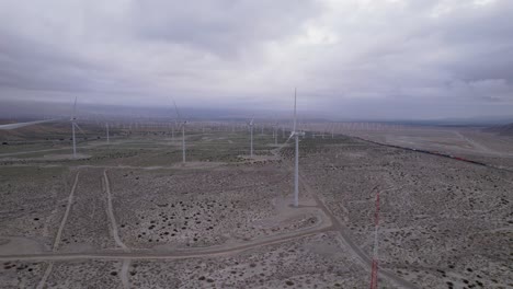 aerial footage of a wind farm in the palm springs desert on a cloudy day, slow dolly shot