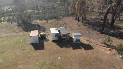 Kangaroos-jumping-over-fence-around-small-buildings-in-outback