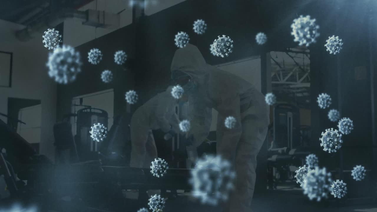 여러 개의 코로나19 세포가 소독제를 사용하여 체육관을 청소하는 보건 노동자 그룹 위에 떠다니고 있습니다.