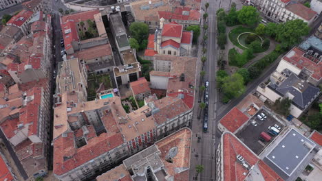 Siguiendo-Un-Tranvía-Desde-Arriba,-Un-Dron-Tomó-El-Centro-De-La-Ciudad-De-Montpellier-Con-Un-Parque.