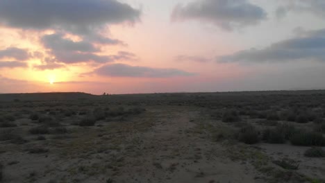 aerial low flying along dirt path in the balochistan landscape against orange yellow sunset skies