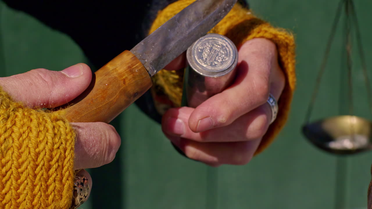 usando un cuchillo para quitar la moneda vikinga tradicional de