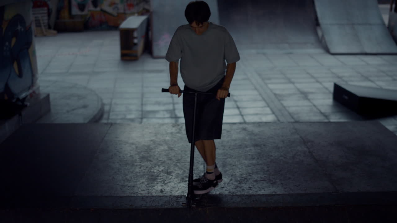 Giovane rider di monopattino che esegue acrobazie su una rampa in uno skate park.