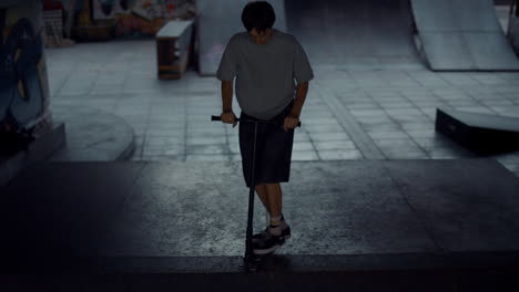 Young-scooter-rider-performing-tricks-on-ramp-at-skate-park.