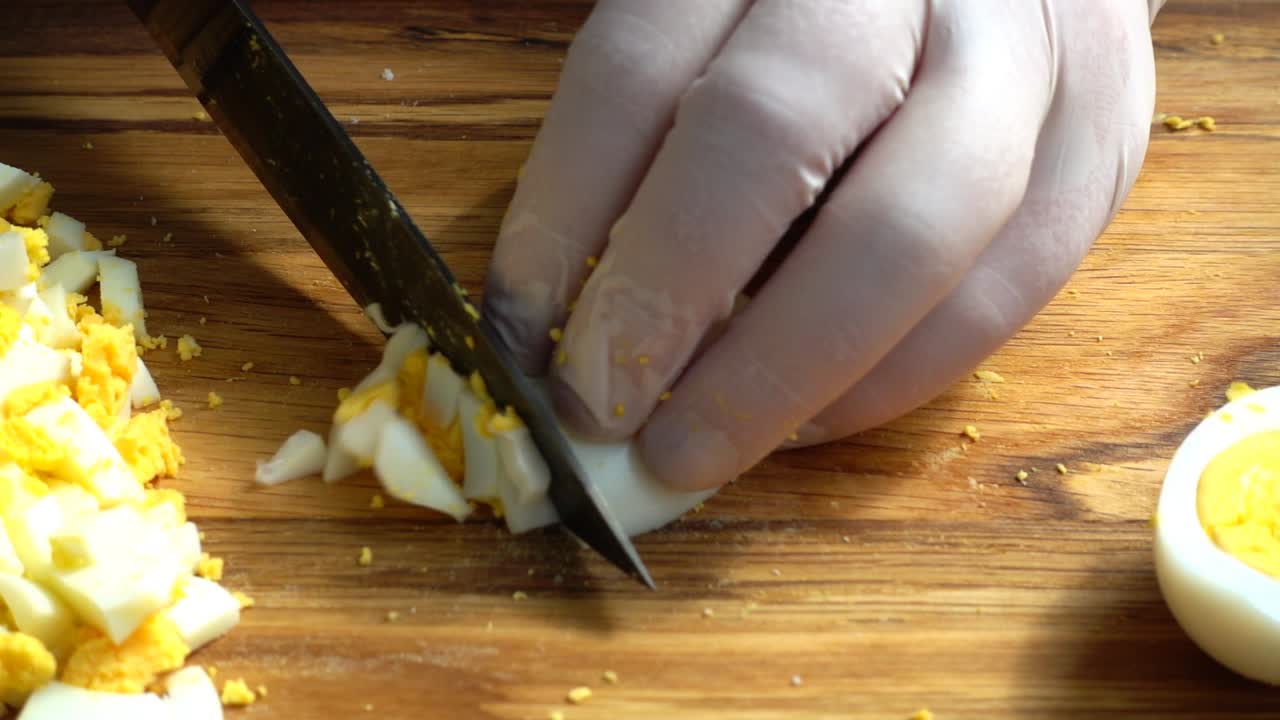 The cook cuts egg on a cutting board
