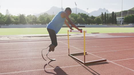 disabled mixed race man with prosthetic legs stretching with a hurdle