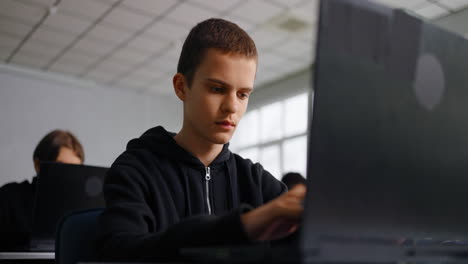 adolescente estudiando en la computadora portátil en el aula