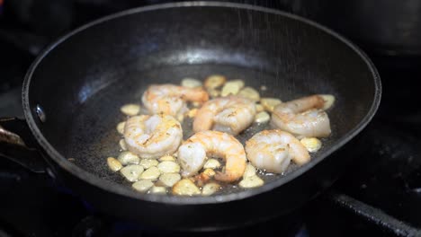 salting and cooking shrimp in a cooking pan in slow motion