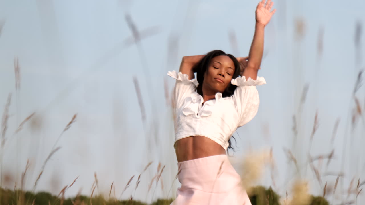 mujer negra jugando en el campo posando para la cámara en un cálido día soleado durante la puesta de sol