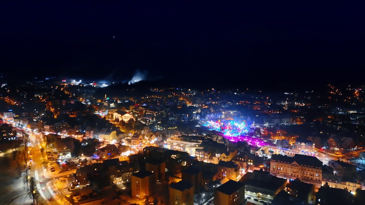 Luminous festive scenery of the cozy town at night. Aerial perspective on the bright panorama illuminated by the festive lights.