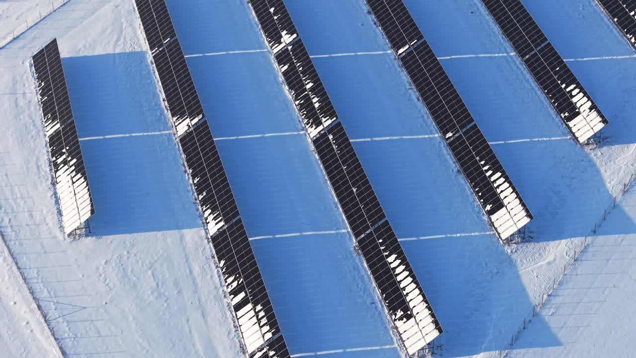 Pannelli solari coperti di neve sotto la brillante luce diurna invernale, ripresa aerea astratta in orbita media.