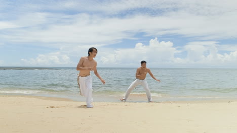 two men dancing capoeira on the beach