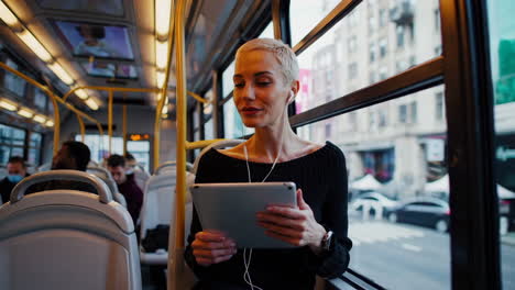 woman on a bus using a tablet and earphones