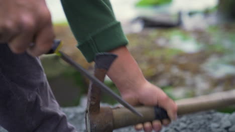 Closeup-handheld-shot-of-a-craftsman-sharping-a-stone-pick-with-a-file,-in-the-town-of-Ancud,-Chiloe-Island