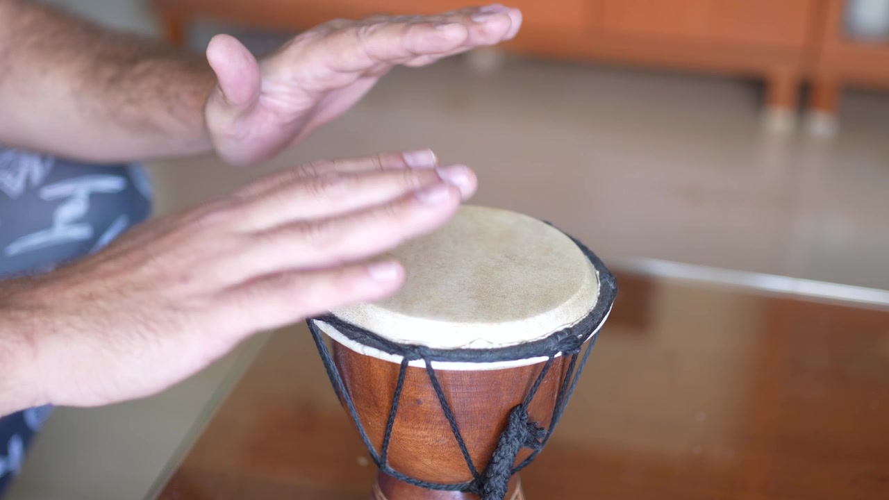 Hands skillfully playing a drum in a cozy home setting filled with artistic expression