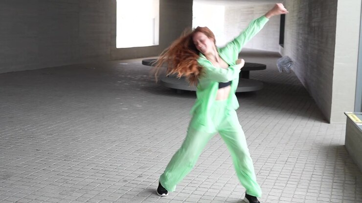 A young woman dances energetically in an urban setting displaying creativity and vibrancy