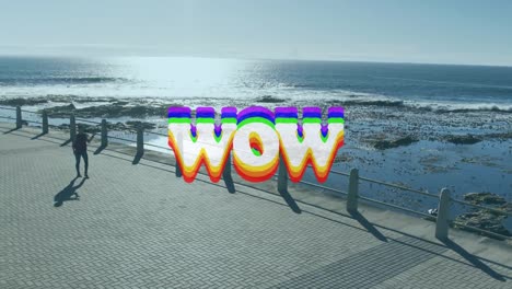 animation of wow text over woman walking, exercising by seaside