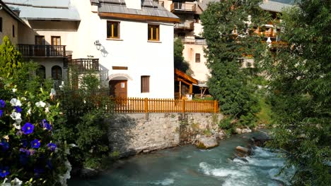 Fachadas-De-Casas-Que-Bordean-Un-Arroyo-De-Montaña-En-Los-Alpes