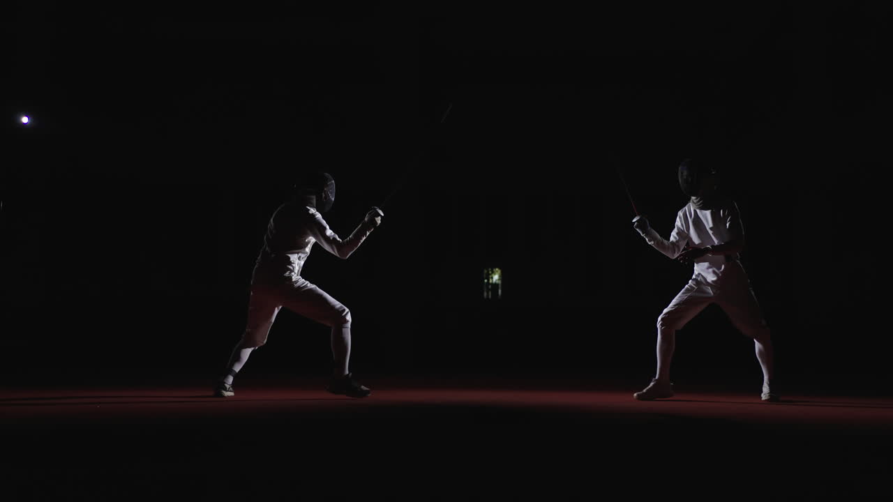 Two fencers compete in a fencing match