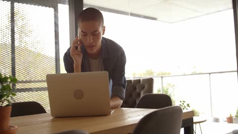 Man-talking-on-mobile-phone-while-using-laptop-4k