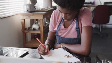 busy african american female worker drawing design of jewellery in jewellery studio in slow motion