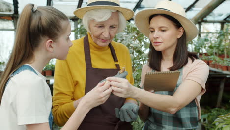 grandmother, daughter, and granddaughter learning about gardening in a greenhouse