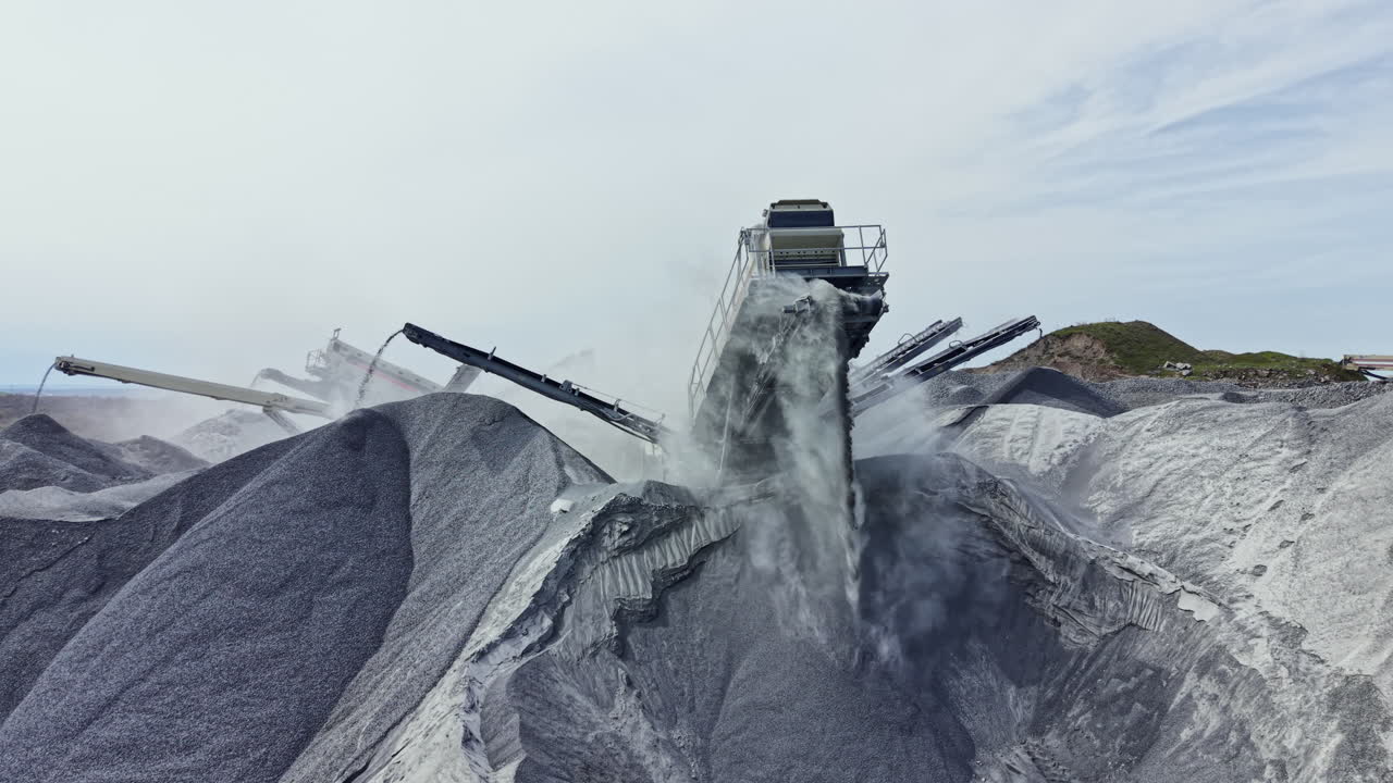 Granite quarry operations take place with heavy machinery moving and processing stone materials in a busy working environment