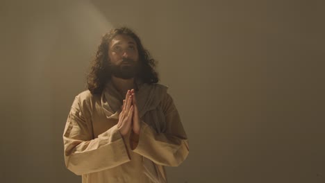 Full-Length-Studio-Portrait-Of-Man-Wearing-Robes-And-Sandals-With-Long-Hair-And-Beard-Representing-Figure-Of-Jesus-Christ-Praying-2