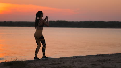 una mujer realiza abdominales al atardecer en la playa en cámara lenta. ejercitar los músculos de las caderas