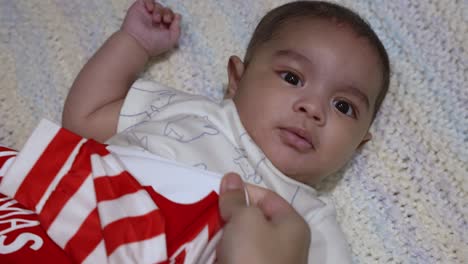 adorable baby boy looking at camera as he is being dressed laying on blanket