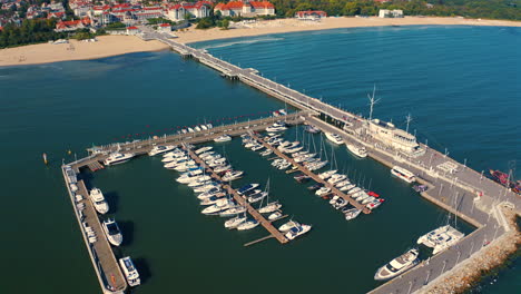 aerial view of drone flying above the marina with moored luxurious yachts and sopot city in the background