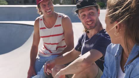 happy caucasian woman and two male friends sitting, talking and spending time together on sunny day