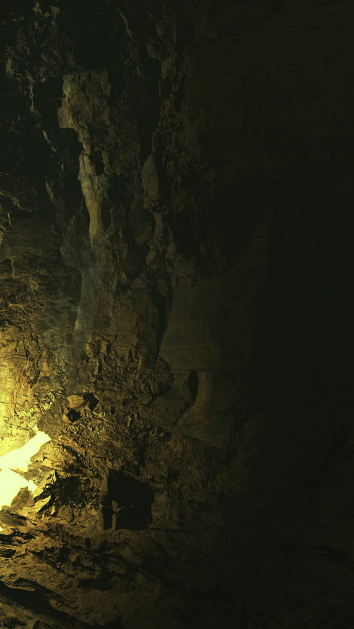 Exploring a dark cave with light illuminating rocky walls and ground