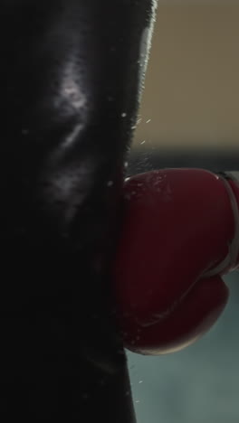 boxing trainer hand in professional glove hits punching bag with power in gym with equipment. male expert goes in for sports and gains muscle mass