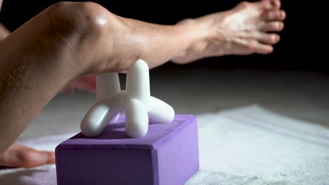 low extreme closeup view of mature woman using a massage tool for myofascial therapy on her leg’s calf