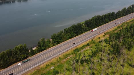 Drone-shot-of-cars-driving-down-the-highway-next-to-the-Columbia-River-near-Portland,-Oregon