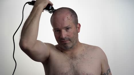 man facing camera while he uses clippers to cut his own hair