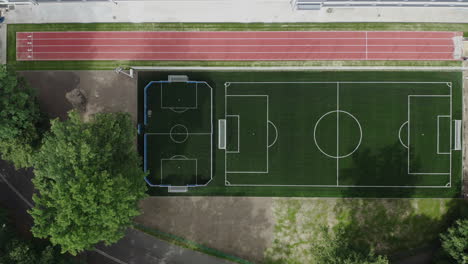 Toma-Aérea-De-Arriba-Hacia-Abajo-De-Un-Nuevo-Campo-De-Fútbol-Y-Pista-De-Atletismo-Al-Lado-De-La-Escuela-Primaria-En-Polonia,-Dron-De-4k