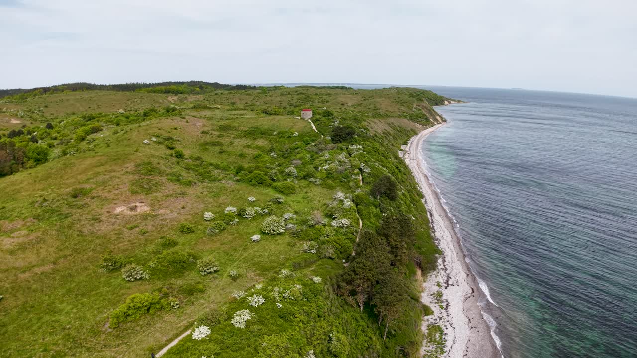Luftaufnahmen mit einer Drohne von grasbewachsenen Küstenklippen und der Küstenlinie mit grünen Feldern und Wildblumen entlang des Meeres