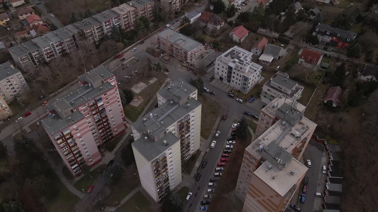Flying over three residential apartment buildings in the middle of a town.