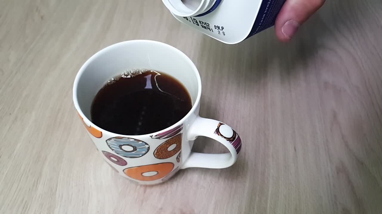 남자 손이 플라스틱 포장에서 우유를 붓는다